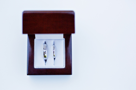 Two white gold rings in a wooden box on white background, view from aboveの写真素材