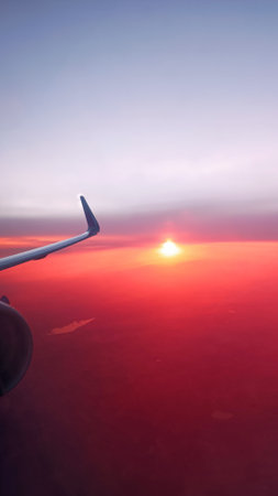Aerial view of sunset and wing of airplane flying above the pink cloudsの写真素材