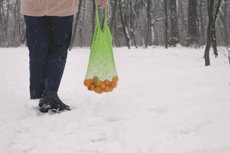 Woman holding a net of mandarins in her handsの写真素材