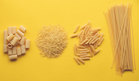 Dry pasta shapes on yellow backgroundの写真素材