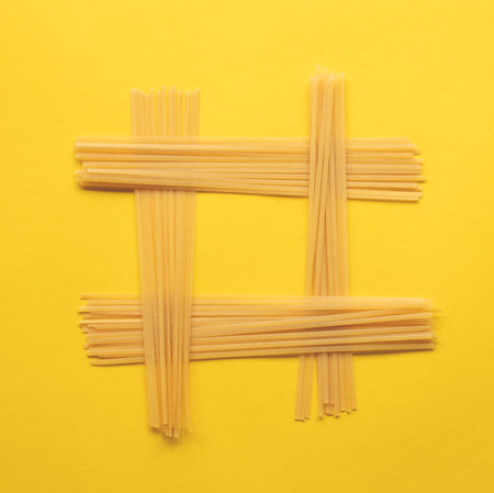 Tic-tac-toe game made with pasta on yellow backgroundの写真素材
