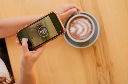 Inspiration during break: photographing cocoa on wooden surface. Close-up of hand taking photo of...