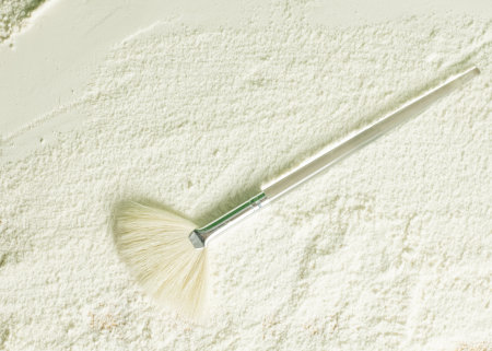 Skincare brush on white clay background