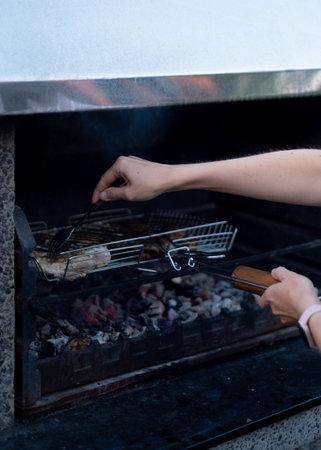 Grilling meat in mesh netting over barbecueの写真素材