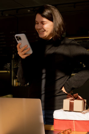 Woman standing by a desk with gifts and laptop