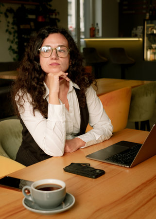 Woman thoughtfully looking away while working on laptop.