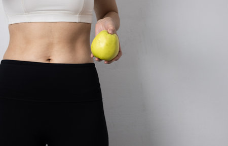 A woman's waist and apple symbolize healthy living. Promoting healthy eatingの写真素材