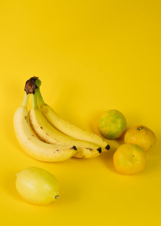 Fresh fruits on yellow background: bananas, tangerines, lemonの写真素材