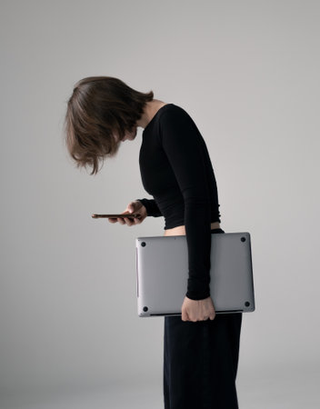 Woman hunched over phone with poor posture, showing unhealthy work habits.の写真素材