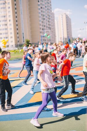 Moscow, Russia - 22 May 2019: Children dancing at school on a holiday in the schoolyard on the background of residential buildings. Focus on girlのeditorial素材