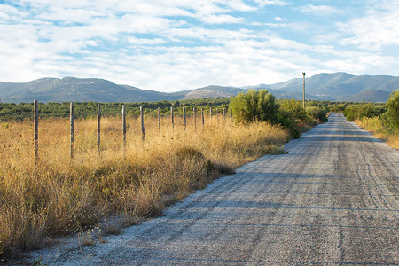 Old Asphalt Road With Mountain Background. Old Fashioned Wooden Fence With a Rural Landscape in the Background.の写真素材