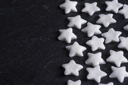 Christmas Background. Sugar Stars Cake Decoration on Dark Stone Close Up. View with Copy Space.の写真素材