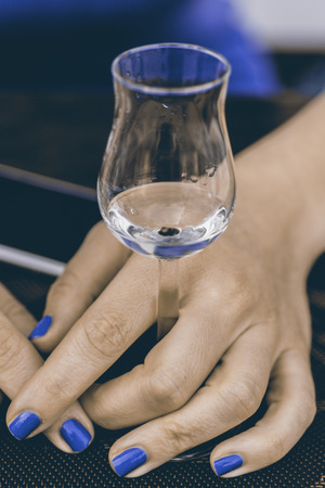 A Glass of Grappa in Womans Hands. Grape Brandy or Schnapps on the Table.の写真素材