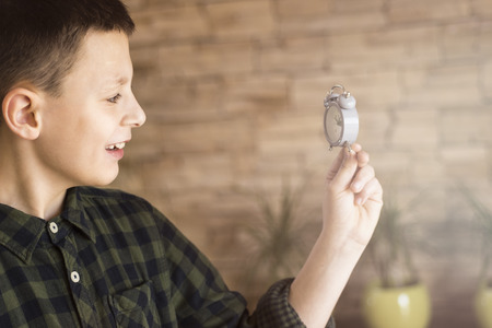 Young Boy Looking at the Small Clock and Smiling. Time Management Concept.の写真素材