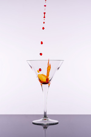 Red Cocktail Splashing From Martini Glass Isolated on White Background. Bar Commercials Concept.の写真素材