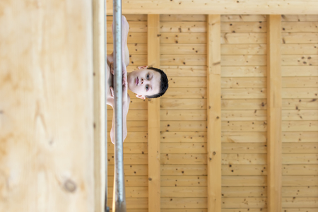 Portrait of Teen Boy Leaning on Fence at Swimming Pool. View from Below.の写真素材