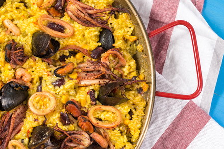 Spanish Seafood Paella in Traditional Pan on Rustic Wooden Tableの写真素材