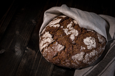 Traditional Whole Grain Rye Bread on Dark Wooden Table Background