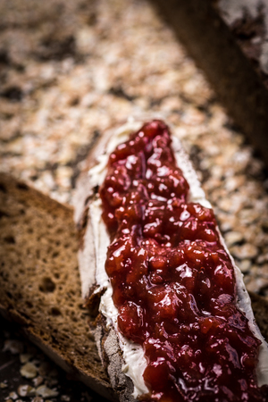 Fruity Jam on Traditional Whole Grain Rye Bread on Dark Wooden Table Backgroundの写真素材