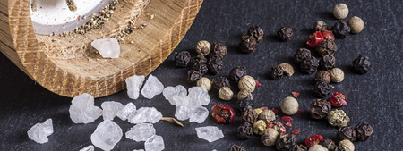 Pepper Mill, Sea Salt and Pepper Grains on Dark Stone Surface Close Upの写真素材