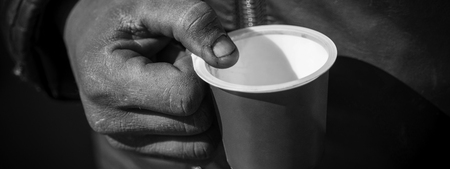 Dirty Beggar Hand Holding Plastic Cup. Poor Man Begging for Money on the Street Close Up.の写真素材