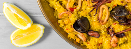 Seafood Paella in Traditional Pan on Rustic Wooden Tableの写真素材