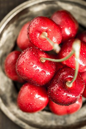 Red Cherries with Water Drops in Rustic Saucerの写真素材