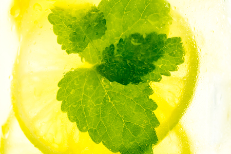 Lemonade Mojito Cocktail with Cold Fresh Ice, Lemon and Mint Leaves in Mason Jar on White Wooden Background. Bright Summer Concept.の写真素材