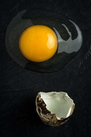 Broken Raw Egg Yolk on Dark Stone Backgroundの写真素材