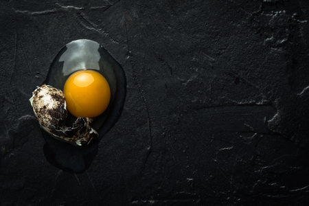 Broken Raw Egg Yolk on Dark Stone Backgroundの写真素材