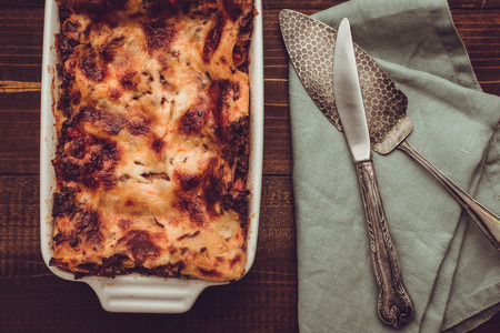 Italian Lasagna Bolognese and Mozzarella Cheese on Rustic Dark Wooden Backgroundの写真素材