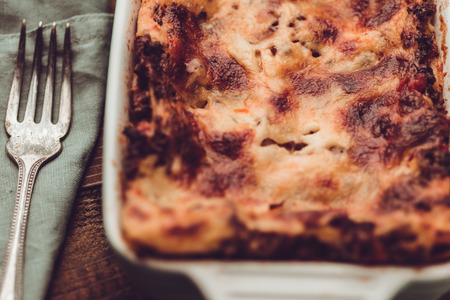 Italian Lasagna Bolognese and Mozzarella Cheese on Rustic Dark Wooden Backgroundの写真素材