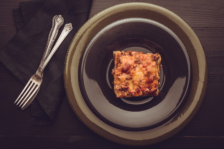 Traditional Italian Lasagna With Minced Beef, Tomato Sauce and Green Basil on Dark Plateの写真素材
