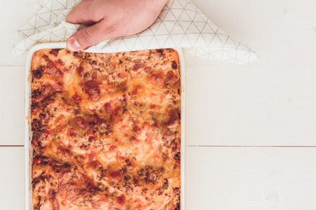 Italian Lasagna Bolognese with Beef, Tomato Sauce and Green Basil on Rustic White Wooden Backgroundの写真素材