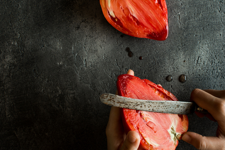 Female Hands Cut Organic Bull's Heart Heirloom Tomato.の写真素材