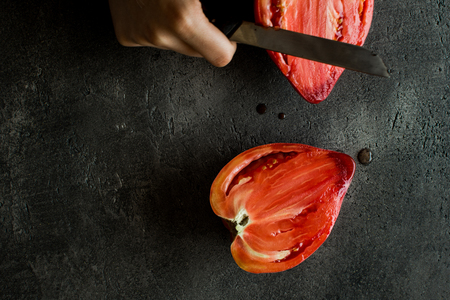 Female Hands Cut Organic Bull's Heart Heirloom Tomato.の写真素材