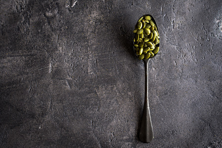 Raw Pumpkin Seeds in Spoon on Rustic Dark Backgroundの写真素材