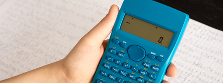 Scientific Calculator in the Action Hands During Mathematical Lesson. School Concept.