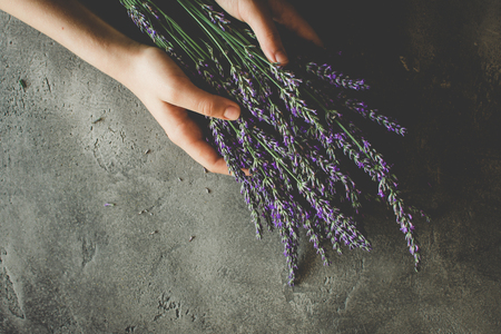 Hands Holding Lavender Bouquet Flowers on Rustic Dark Background. Skin and Hair Care.の写真素材