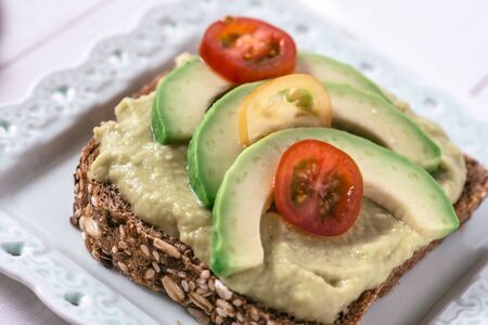 Organic Green Guacamole Avocado Spread and Slices with Fresh Cherry Tomato and Black Sesame. Healthy...