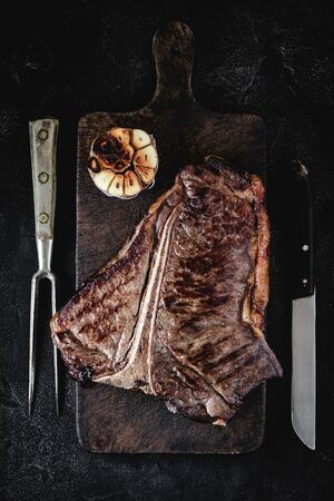 Grilled Premium Dry Aged T-bone Steak on Dark Rustic Chopping Board. USDA Prime Beef.の写真素材