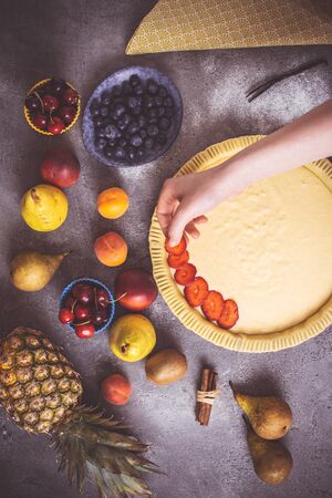 Female Hands Prepare Fruit Pie with Colorful Fruits and Fresh Dough. Healthy Food Concept.の写真素材