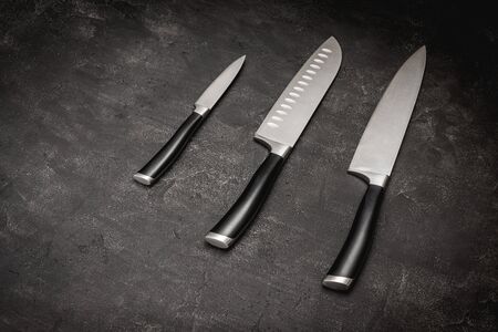 Modern Kitchen Knives Set on Dark Stone Background. Chef's Knives Concept.の写真素材