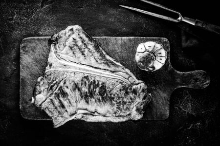 Grilled Dry Aged Premium T-bone Steak on Dark Rustic Chopping Board. Black and White USDA Prime Beef.の写真素材