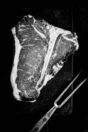 Dry Aged Premium Raw T-bone Steak on Rustic Kitchen Chopping Board. Black and White USDA Prime Beef.の写真素材