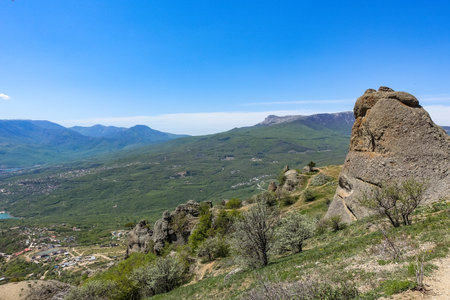 Ancient limestone high mountains of rounded shape in the air haze. The Valley of Ghosts. Demerji. Green trees and bushes in the foreground. May 2021. Crimea.の写真素材