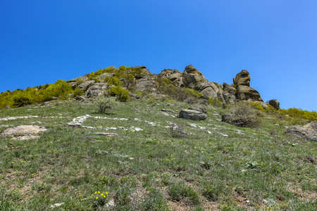 Ancient limestone high mountains of rounded shape in the air haze. The Valley of Ghosts. Demerji. Green trees and bushes in the foreground. May 2021. Crimea.の写真素材