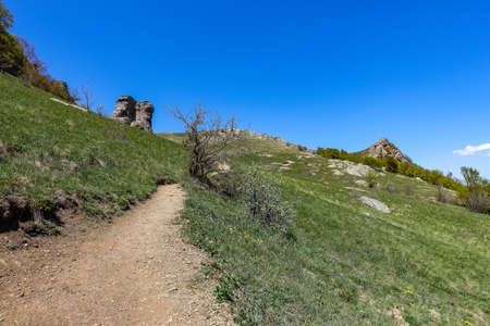 Ancient limestone high mountains of rounded shape in the air haze. The Valley of Ghosts. Demerji. Green trees and bushes in the foreground. May 2021. Crimea.の写真素材
