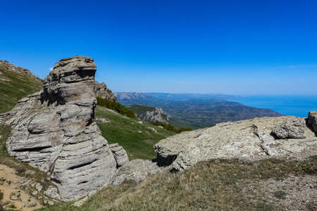 Ancient limestone high mountains of rounded shape in the air haze. The Valley of Ghosts. Demerji. Green trees and bushes in the foreground. May 2021. Crimea.の写真素材