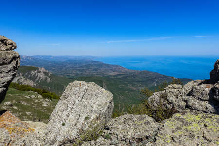 Ancient limestone high mountains of rounded shape in the air haze. The Valley of Ghosts. Demerji. Green trees and bushes in the foreground. May 2021. Crimea.の写真素材